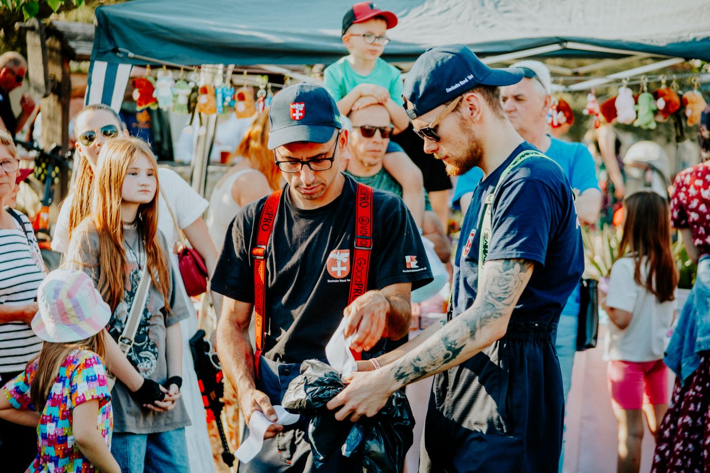 People browse an outdoor community market in daylight.