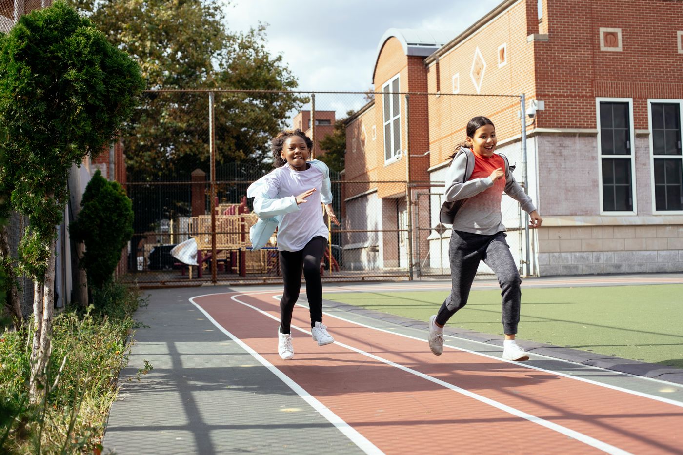 Children run on a marked outdoor school track.
