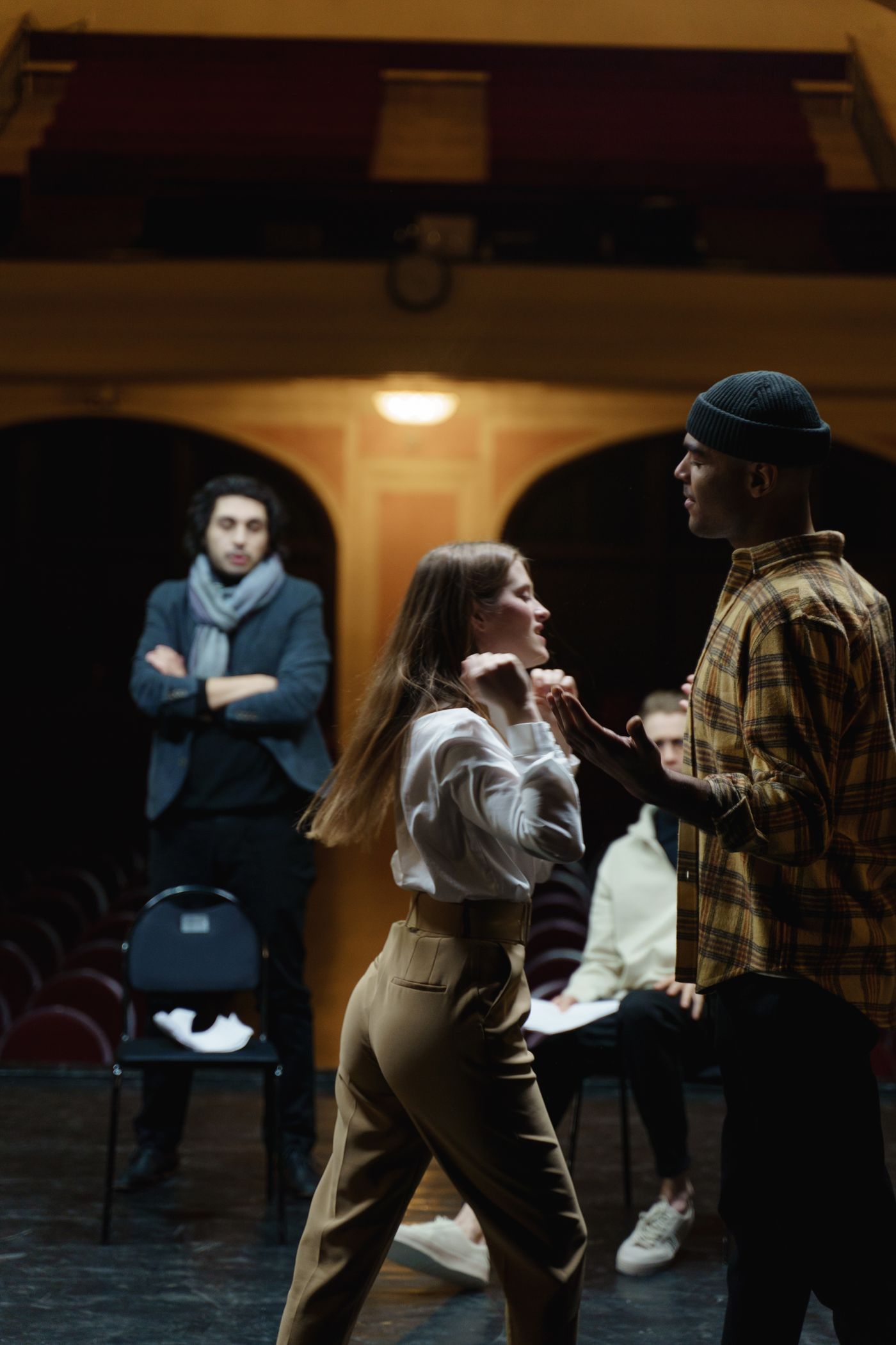 Actors rehearse a dramatic scene on a theater stage.