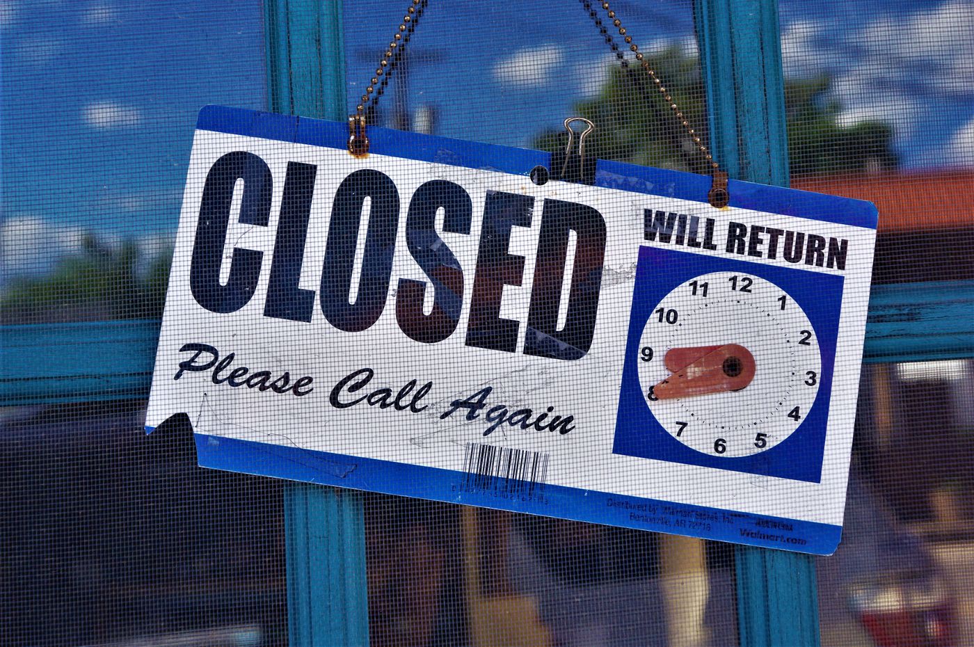 A generic “Closed” sign hangs on a glass door.