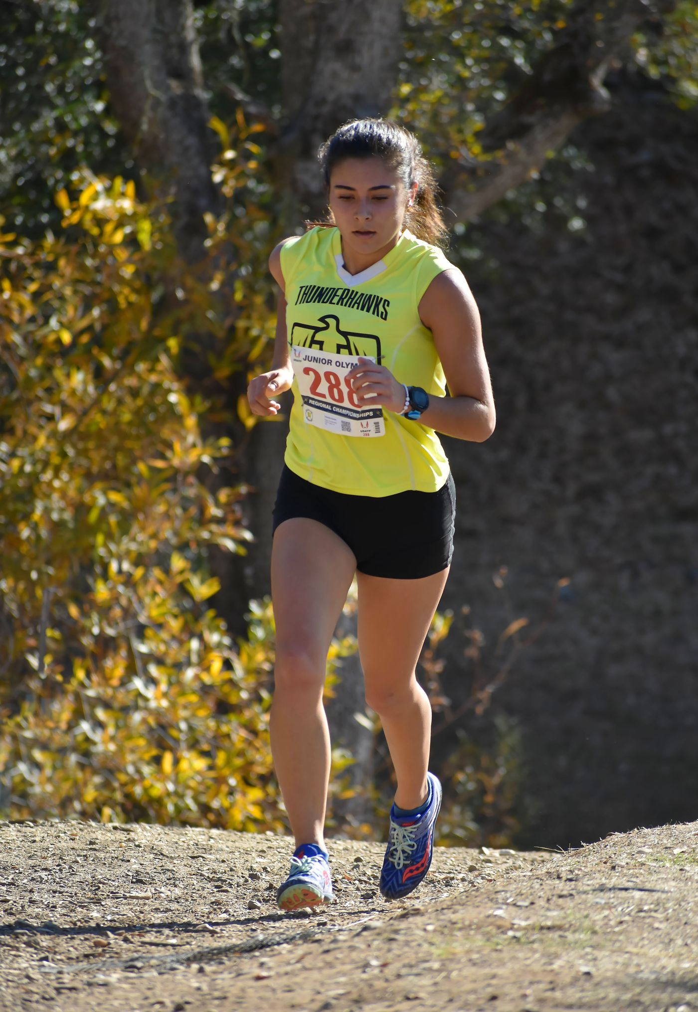 A cross-country runner wearing a race bib on an outdoor course.