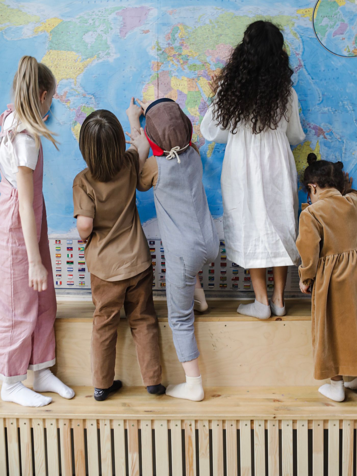 Children examine a world map during an indoor learning activity.